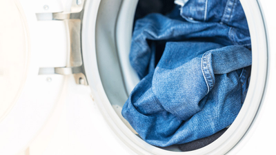 A person washing a pair of jeans in a washing machine